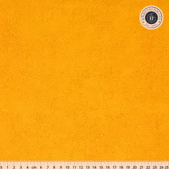 Goldgelber Baumwollstoff mit feinem Spotted-Tupfendruck in Dunkelorange, mit Zentimeter-Maßstab am unteren Bildrand.